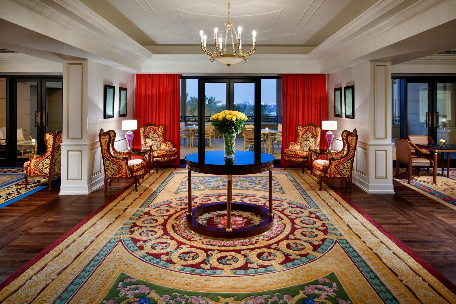A Palazzo Versace Dubai salon with gold and red Versace furnishings, a patterned rug and a chandelier
